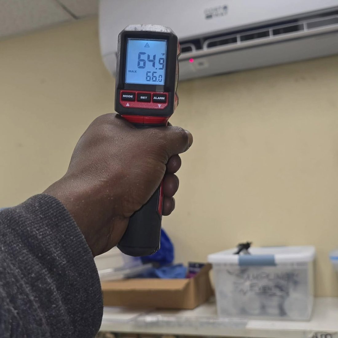 An infrared thermometer reading 64.9 at a running mini-split head