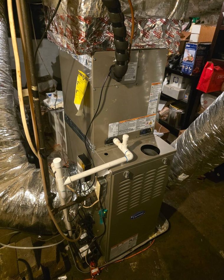 A Carrier furnace in a basement with new duct and a condensate line